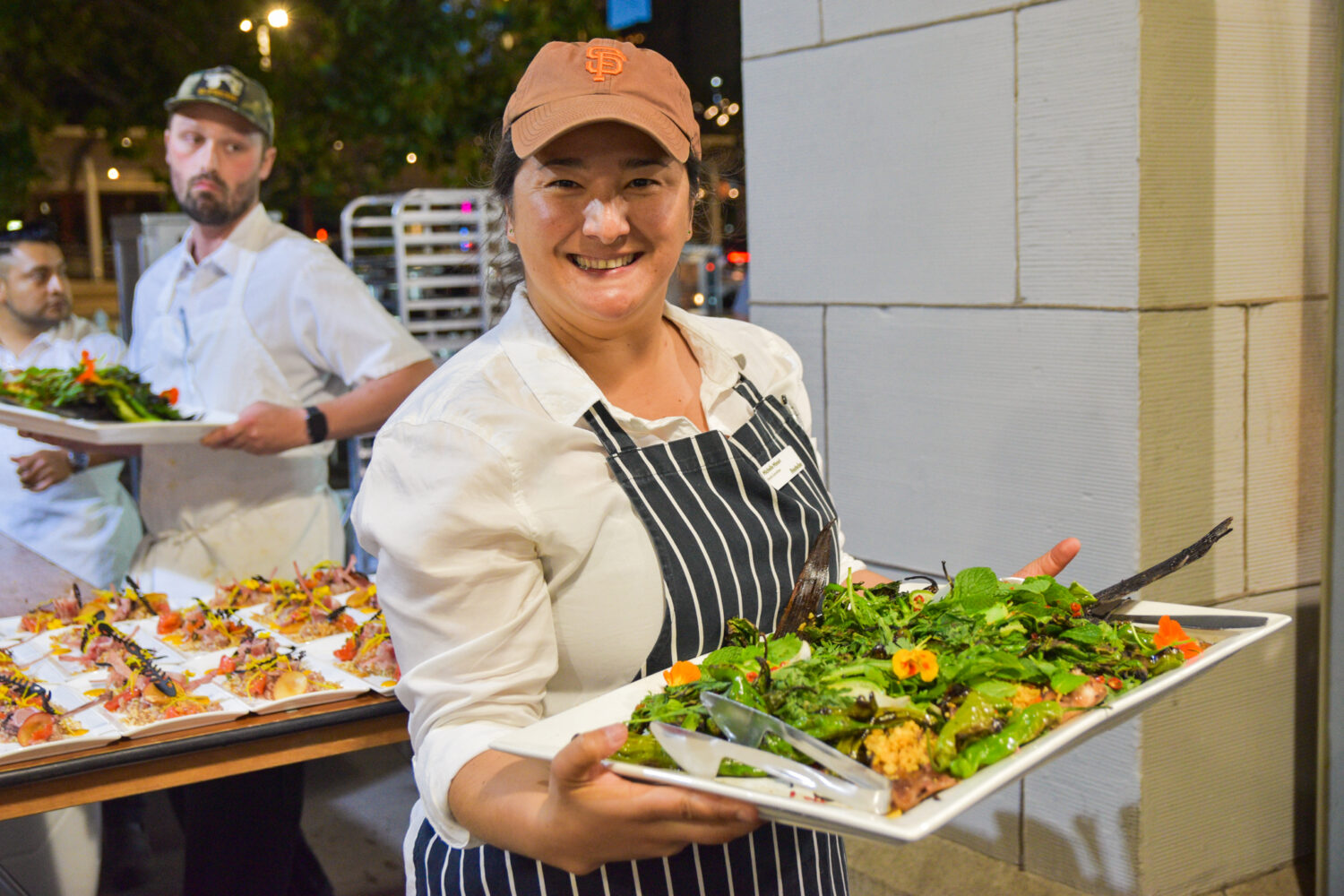 Chef Michelle Minori holding a platter of salad at Foodwise Sunday Supper